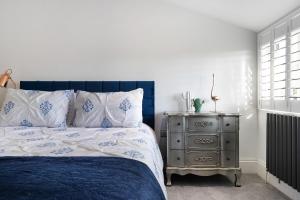 a bedroom with a blue and white bed and a nightstand at Priory Farm Cottage in Colchester