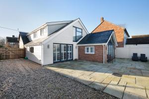 a white house with a garage and a driveway at Priory Farm Cottage in Colchester