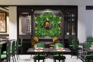 Hanoi Center Silk Classic Hotel & Travel في هانوي: غرفة طعام مع طاولات وكراسي خضراء