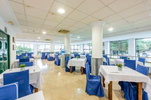 un restaurante con mesas blancas y sillas azules en Hotel Toboso Almuñécar en Almuñécar