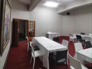 un comedor con mesas blancas y sillas blancas en Indaba Hotel - Sasolburg en Sasolburg