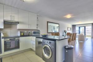 a kitchen with a washing machine in the middle at Stylish sea-facing apartment with underground parking in Cape Town