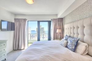a bedroom with a large bed with a large window at Stylish sea-facing apartment with underground parking in Cape Town