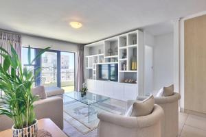 sala de estar con muebles blancos y mesa de cristal en Stylish sea-facing apartment with underground parking, en Ciudad del Cabo