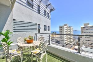 a patio with a table and chairs on a balcony at Stylish sea-facing apartment with underground parking in Cape Town