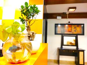 uma mesa amarela com um vaso com uma planta em Athasri Hotel HSR Layout em Bangalore