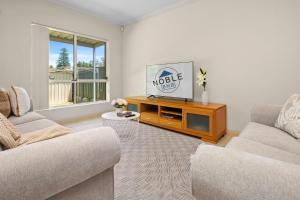 a living room with two couches and a tv at Beaumont Bliss: 4BR 2 5BA Family Retreat in Glenunga