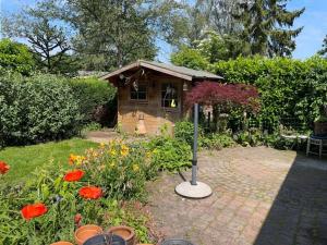 a garden with a small shed with flowers in front at Spacious Chalet in Garderen with Fenced Garden in Garderen