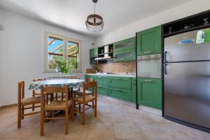 een keuken met groene kasten en een tafel met stoelen bij Villa del Sol by Perle di Puglia in Otranto