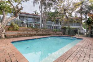 a swimming pool in front of a house with trees at UNIT 1 @ Springvale Complex, Zinkwazi Beach in Zinkwazi Beach