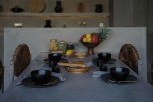 einen Tisch mit schwarzen Tassen und Tellern und eine Schale Obst in der Unterkunft The Konkret Lombok in Kuta Lombok