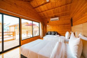 two beds in a room with a large window at JSK Mantanani Island Resorts in Mantanani Island 
