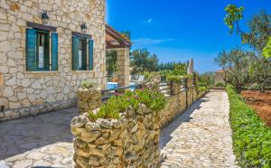 a stone wall next to a house with flowers at Villa Lida Aresti in Agios Leon