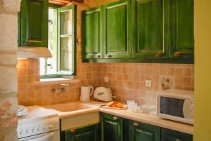 a kitchen with green cabinets and a microwave at Villa Lida Aresti in Agios Leon