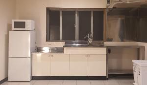 a kitchen with a white refrigerator and a microwave at CHEZ LILY【旧:北海莊】 in Naha