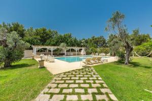 a swimming pool in a yard with chairs and trees at Masseria Cucuruzza Boutique Hotel in Felline