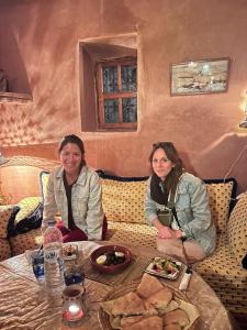 dos mujeres sentadas en una mesa con platos de comida en Kasbah Tigmi El Janoub, en Aït Ben Haddou