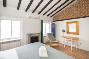 a bedroom with a bed and a chair and a fireplace at Figueroa in Madrid