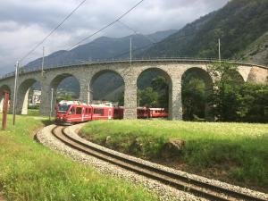 a red train is on the tracks under a bridge at Osteria Del Centro in Brusio
