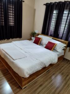 um quarto com uma cama grande com lençóis brancos e almofadas vermelhas em antelopewildstay em Kutta