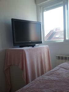 TV de pantalla plana sentada en una mesa junto a una ventana en CALIDAS HABITACIONES DOBLES, BAÑO PRIVADO y PATIO, en Villalbilla