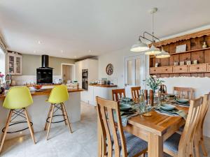 a kitchen and dining room with a wooden table and yellow chairs at 4 Bed in Richmond 90852 in Richmond