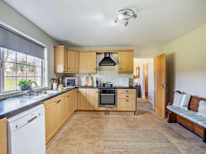 a kitchen with wooden cabinets and a sink and a window at 3 Bed in Cockermouth 90920 in Tallentire