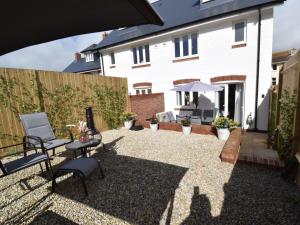 a patio with chairs and an umbrella in front of a house at 3 Bed in Lulworth Cove 91200 in West Lulworth