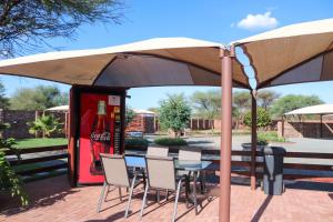 a table and chairs under an umbrella with a coke machine at Big D Accommodation & guesthouse in Northam