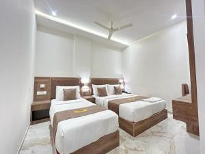 two beds in a room with white walls at MIG SUITES in Mumbai