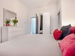 a white bedroom with a large white bed with red pillows at 1 Bed in Allonby 91113 in Allonby