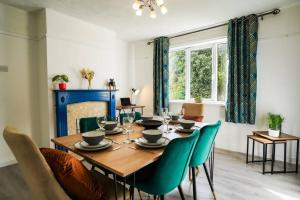 a dining room with a wooden table and green chairs at Stylish 3-Bed Home near Anfield with Parking in Walton on the Hill