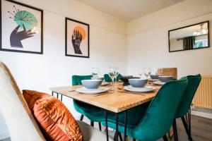 a dining room with a wooden table and green chairs at Stylish 3-Bed Home near Anfield with Parking in Walton on the Hill