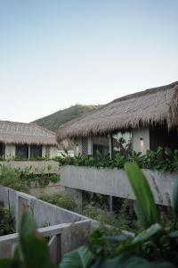 zwei Häuser mit Strohdächern, einem Zaun und Pflanzen in der Unterkunft The Konkret Lombok in Kuta Lombok