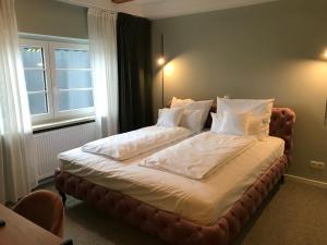 een bed met witte lakens en kussens in een slaapkamer bij Lèvres Hotel in Schrobenhausen