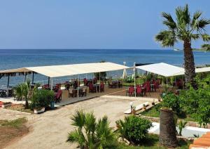 a restaurant with tables and chairs and the ocean at Kefalonia Beach Hotel & Bungalows in Lixouri