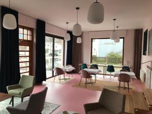 a living room with chairs and tables and a pink floor at Lèvres Hotel in Schrobenhausen