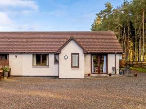 a white house with a brown roof on a driveway at 2 Bed in Culbokie 90813 in Culbokie