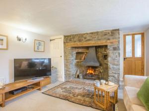 a living room with a stone fireplace and a tv at 3 Bed in Weare Giffard 90864 in Weare Giffard