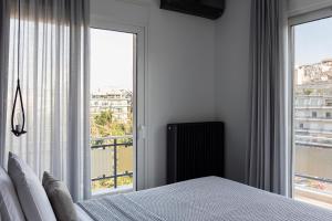 ein Schlafzimmer mit einem Bett und einem großen Fenster in der Unterkunft Casa Athénée in Athen