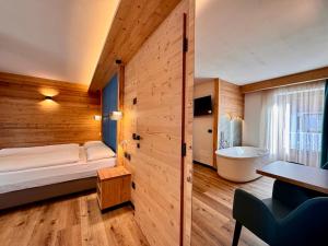 um quarto com uma cama e uma banheira num quarto em Dolomiti Luxury Mountain View em Canazei