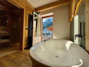 uma grande banheira branca numa casa de banho com uma janela em Dolomiti Luxury Mountain View em Canazei