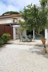 um pátio com uma mesa e cadeiras em frente a uma casa em GASREM - Golfe de St-Tropez - Mazet dans domaine avec piscine et tennis em Gassin