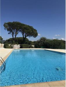 uma grande piscina azul com árvores ao fundo em GASREM - Golfe de St-Tropez - Mazet dans domaine avec piscine et tennis em Gassin