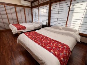 two beds sitting in a room with windows at Hondori Inn in Hiroshima