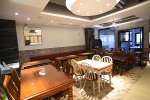 安平商旅Choona Hotel Anping في آنبينغ: غرفة طعام مع طاولات وكراسي خشبية