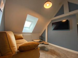 a living room with a couch and a tv at Hôtel du Musée in Granville