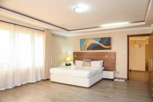 a bedroom with a large white bed and a painting at Eldon Suites & Apartments By MOKAWA in Nairobi +91 photos
