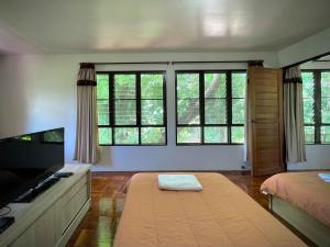 1 dormitorio con 1 cama, TV y ventanas en เรือนกิ่งไผ่ (กรรณิการ์ แพร่ โฮมสเตย์), en Ban Kha Ngam