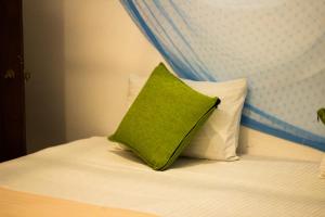 a green pillow sitting on top of a bed at Muru's Place in Dickwella